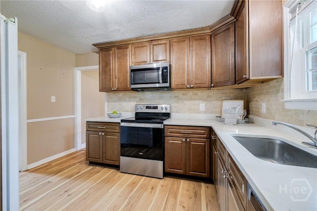 322 Suncrest Blvd, Savannah, GA 31410 - kitchen featuring stainless steel appliances, light wood-style flooring, backsplash, light countertops, and a textured ceiling