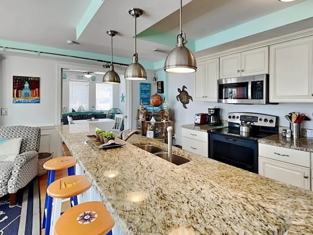 1415 Butler Ave Unit 1, Tybee Island, GA 31328 - kitchen with stainless steel microwave, electric stove, white cabinets, light stone counters, and a kitchen island with sink
