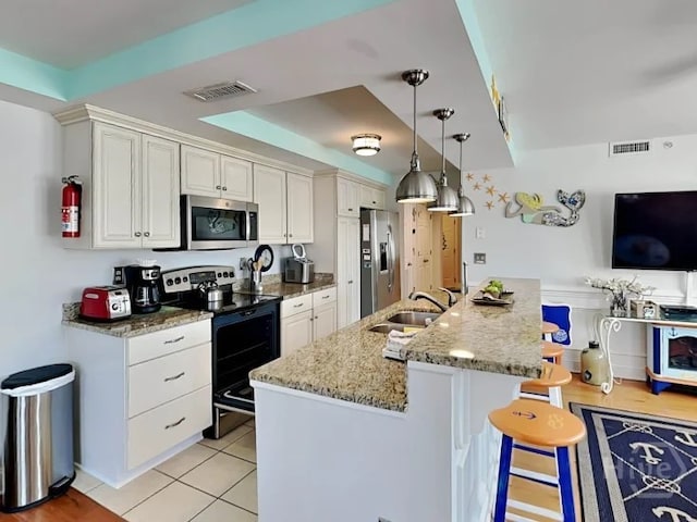 1415 Butler Ave Unit 1, Tybee Island, GA 31328 - kitchen featuring appliances with stainless steel finishes, a kitchen bar, light stone counters, white cabinets, and an island with sink