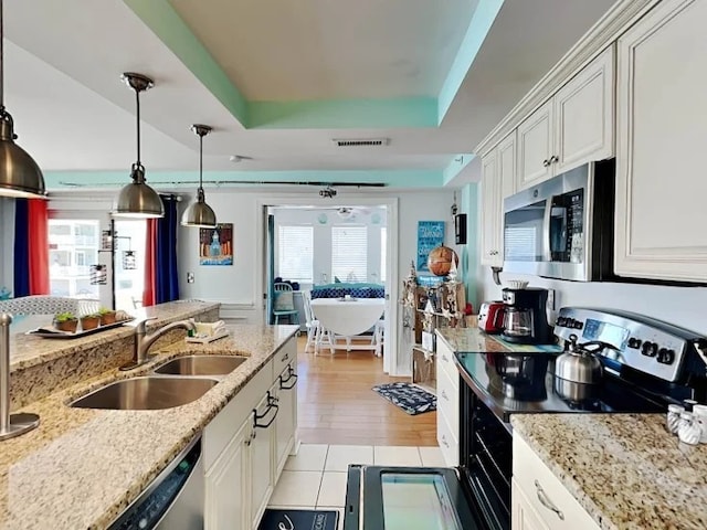 1415 Butler Ave Unit 1, Tybee Island, GA 31328 - kitchen with appliances with stainless steel finishes, a raised ceiling, white cabinets, decorative light fixtures, and light stone counters
