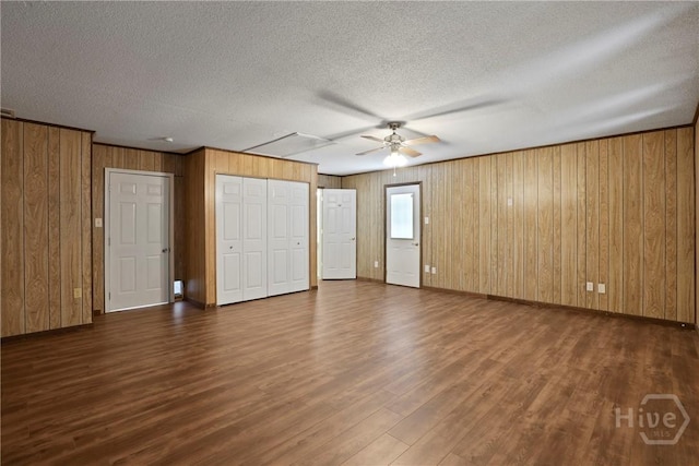 13609 Rockingham Ct, Savannah, GA 31419 - unfurnished bedroom with wood walls, dark wood finished floors, a textured ceiling, and multiple closets