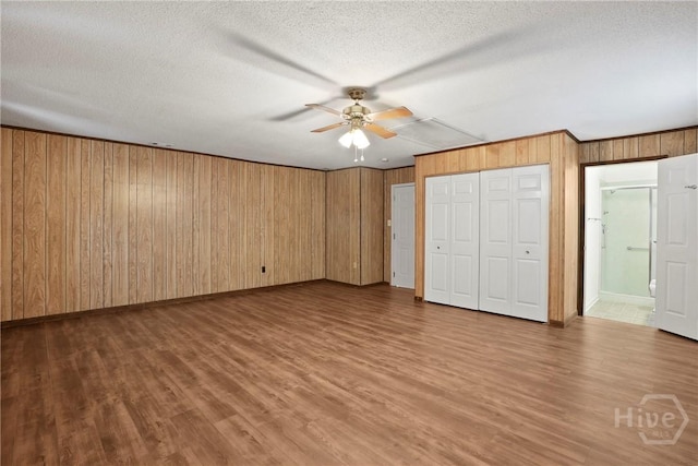13609 Rockingham Ct, Savannah, GA 31419 - unfurnished bedroom featuring wood walls, wood finished floors, a textured ceiling, connected bathroom, and ceiling fan