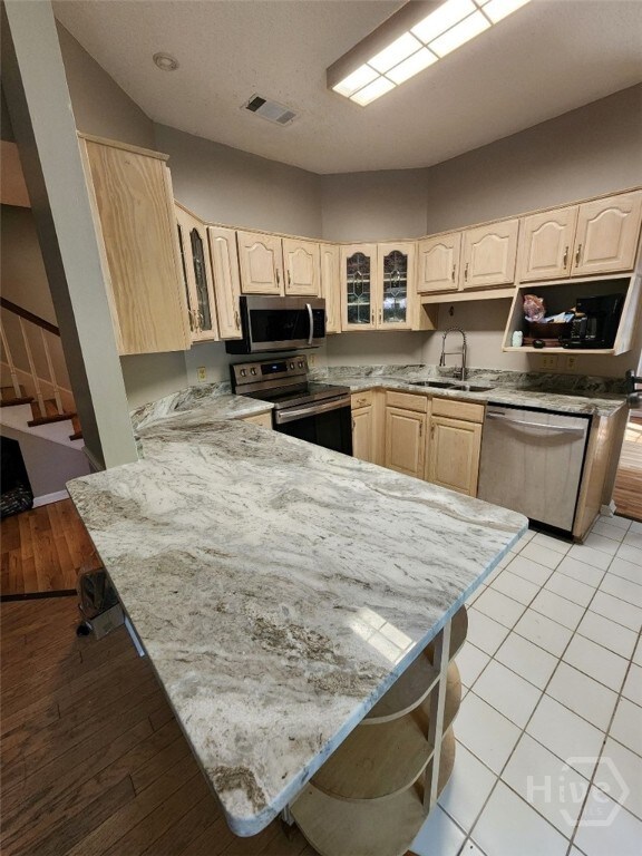 123 Companion Way, Savannah, GA 31419 - kitchen with stainless steel appliances, light brown cabinets, a peninsula, and glass insert cabinets