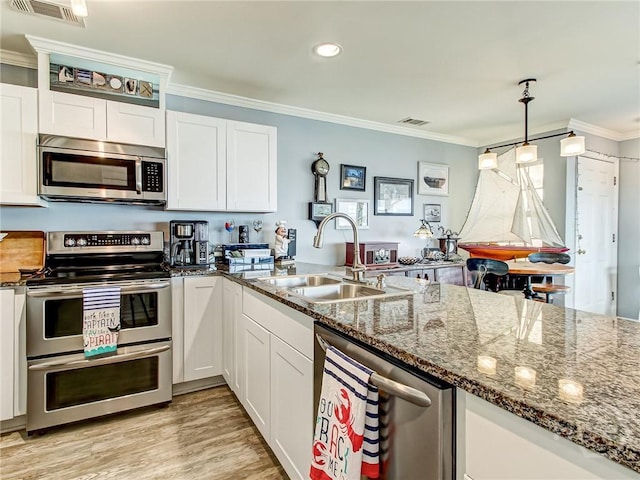 8 Silver Ave Unit 9, Tybee Island, GA 31328 - kitchen with appliances with stainless steel finishes, crown molding, white cabinets, dark stone countertops, and light wood finished floors