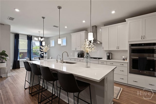 742 Longleaf Dr, Richmond Hill, GA 31324 - kitchen with wall chimney range hood, double oven, tasteful backsplash, white cabinetry, and a breakfast bar area