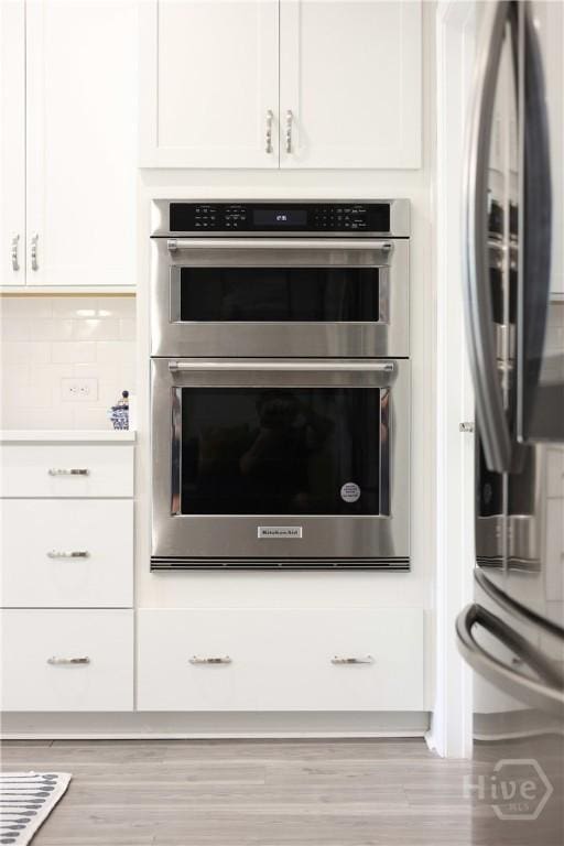 742 Longleaf Dr, Richmond Hill, GA 31324 - kitchen view of stainless steel appliances, white cabinets, wood finished floors, and tasteful backsplash
