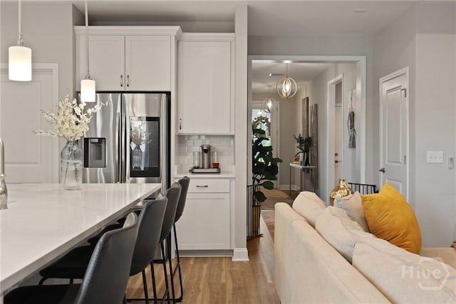 742 Longleaf Dr, Richmond Hill, GA 31324 - kitchen featuring stainless steel fridge, light wood-style floors, white cabinets, a kitchen breakfast bar, and backsplash