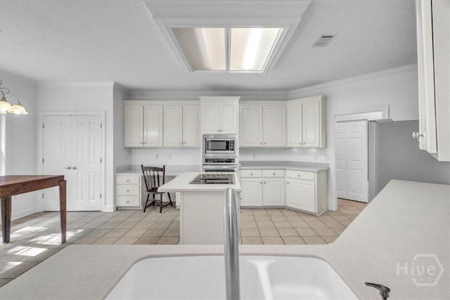 80 Windsong Dr, Richmond Hill, GA 31324 - kitchen featuring appliances with stainless steel finishes, white cabinets, light countertops, ornamental molding, and light tile patterned floors