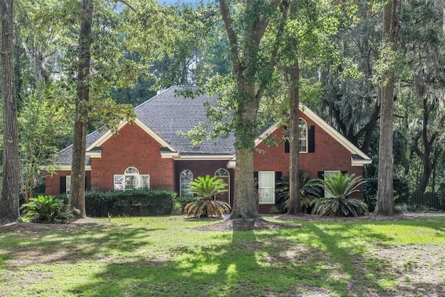 80 Windsong Dr, Richmond Hill, GA 31324 - view of front of house with a front yard, brick siding, and a shingled roof