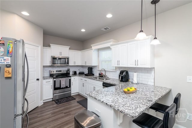 333 Providence Trce, Statesboro, GA 30461 - kitchen with stainless steel appliances, a peninsula, white cabinetry, dark wood-type flooring, and tasteful backsplash