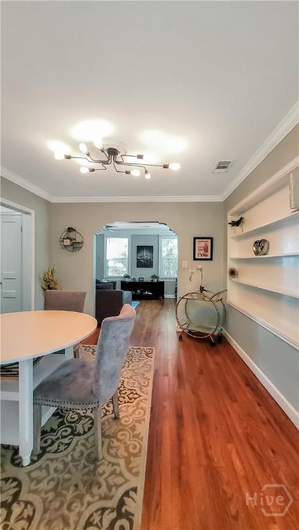202 Columbus Dr, Savannah, GA 31405 - dining space with crown molding, arched walkways, wood finished floors, and built in shelves