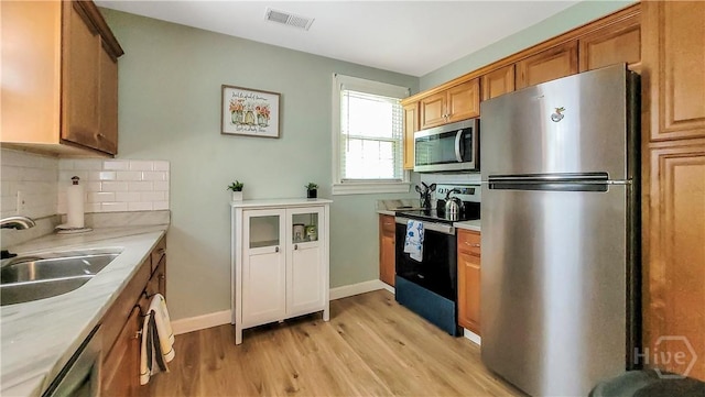 202 Columbus Dr, Savannah, GA 31405 - kitchen with stainless steel appliances, light wood-style floors, light countertops, backsplash, and brown cabinets