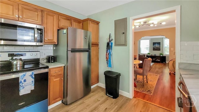 202 Columbus Dr, Savannah, GA 31405 - kitchen featuring appliances with stainless steel finishes, electric panel, light wood-type flooring, arched walkways, and decorative backsplash