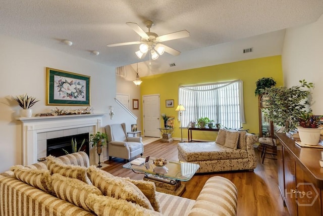 12 Crossing Dr, Richmond Hill, GA 31324 - living room with a textured ceiling, wood finished floors, a ceiling fan, and a tiled fireplace