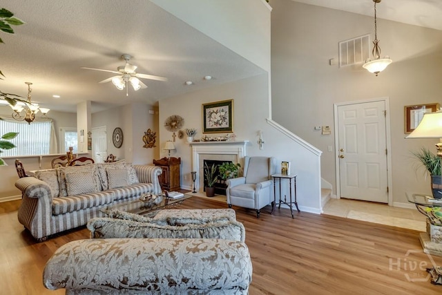 12 Crossing Dr, Richmond Hill, GA 31324 - living area with light wood-type flooring, ceiling fan, a fireplace with flush hearth, stairway, and a chandelier