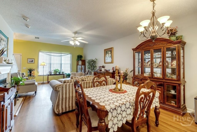 12 Crossing Dr, Richmond Hill, GA 31324 - dining room with light wood-style flooring, a chandelier, a ceiling fan, a textured ceiling, and a tile fireplace