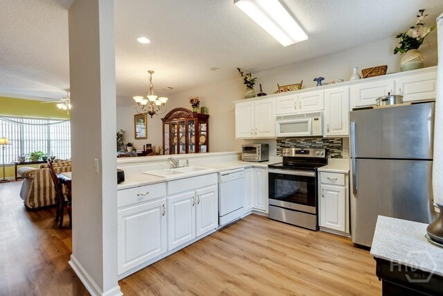 12 Crossing Dr, Richmond Hill, GA 31324 - kitchen with stainless steel appliances, light wood-type flooring, light countertops, white cabinetry, and tasteful backsplash