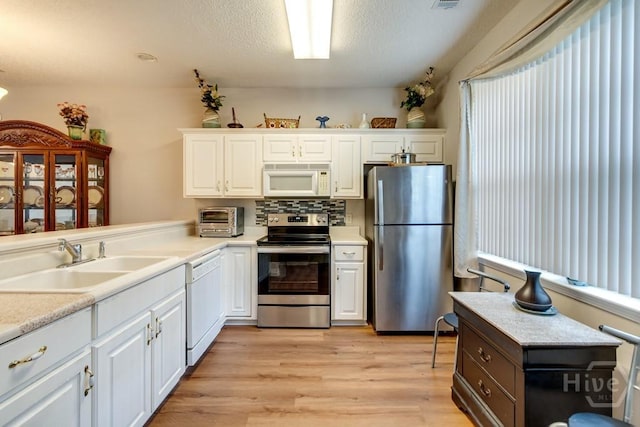 12 Crossing Dr, Richmond Hill, GA 31324 - kitchen with stainless steel appliances, white cabinetry, light wood-style flooring, light countertops, and a textured ceiling