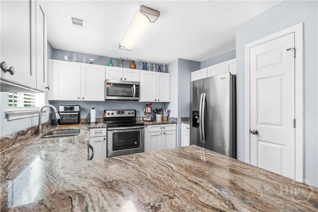139 Crossover Ln, Savannah, GA 31410 - kitchen with stainless steel appliances, light stone countertops, white cabinets, and a textured ceiling