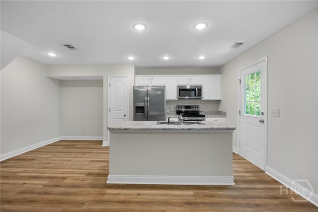 13 Abaco Ct, Savannah, GA 31419 - kitchen featuring appliances with stainless steel finishes, white cabinetry, wood finished floors, a center island with sink, and recessed lighting