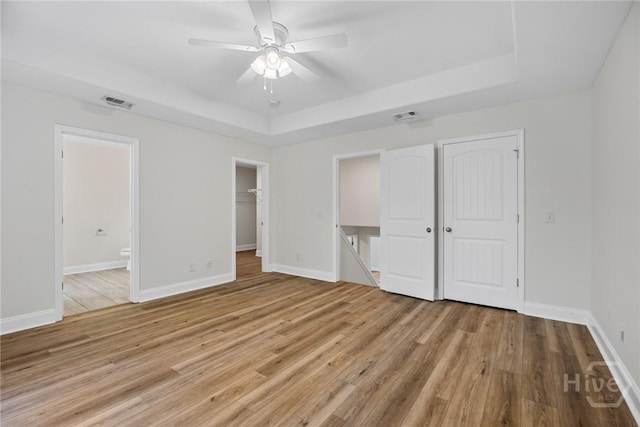 13 Abaco Ct, Savannah, GA 31419 - unfurnished bedroom featuring a tray ceiling, light wood finished floors, connected bathroom, and ceiling fan