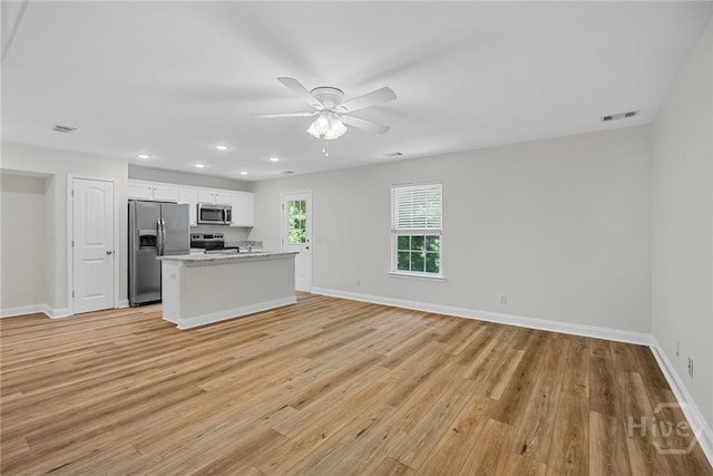 13 Abaco Ct, Savannah, GA 31419 - kitchen featuring appliances with stainless steel finishes, ceiling fan, light wood-style flooring, white cabinets, and a kitchen island with sink