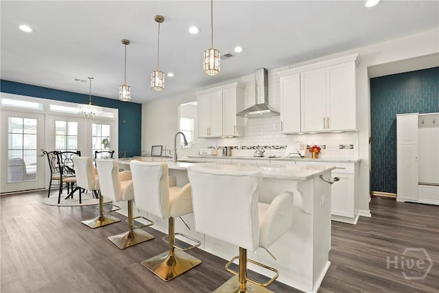 11 Shoefstall St, Savannah, GA 31407 - kitchen featuring wall chimney exhaust hood, dark wood-style floors, recessed lighting, an island with sink, and white cabinets