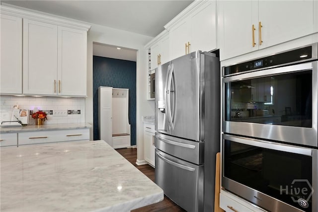 11 Shoefstall St, Savannah, GA 31407 - kitchen with appliances with stainless steel finishes, white cabinets, tasteful backsplash, light stone counters, and dark wood-style floors