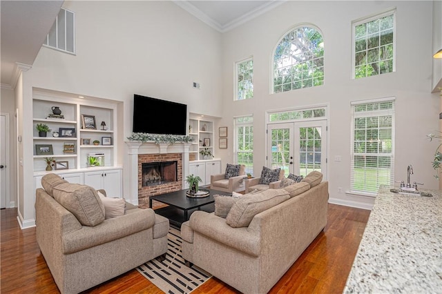 210 Windsong Dr, Richmond Hill, GA 31324 - living room with ornamental molding, dark wood-type flooring, a brick fireplace, built in shelves, and a towering ceiling