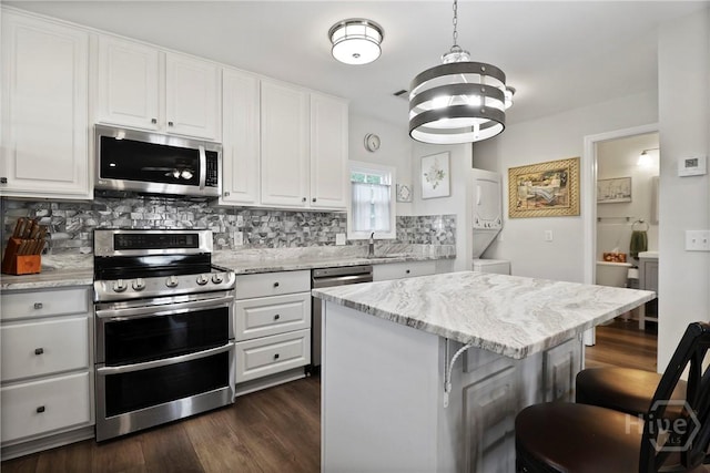 536 E Harris St, Savannah, GA 31401 - kitchen with appliances with stainless steel finishes, stacked washer / drying machine, decorative backsplash, a breakfast bar, and white cabinets
