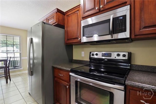 140 Kettle Creek Ln, Midway, GA 31320 - kitchen featuring stainless steel appliances, dark countertops, light tile patterned floors, and a textured ceiling