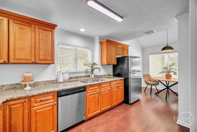3005 River Dr Unit 302, Savannah, GA 31404 - kitchen featuring stainless steel appliances, a textured ceiling, wood finished floors, brown cabinetry, and light stone counters