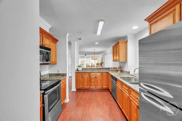 3005 River Dr Unit 302, Savannah, GA 31404 - kitchen featuring stainless steel appliances, wood finished floors, light stone countertops, a textured ceiling, and pendant lighting