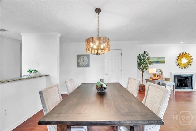 3005 River Dr Unit 302, Savannah, GA 31404 - dining space featuring a chandelier, wood finished floors, a textured ceiling, and a fireplace