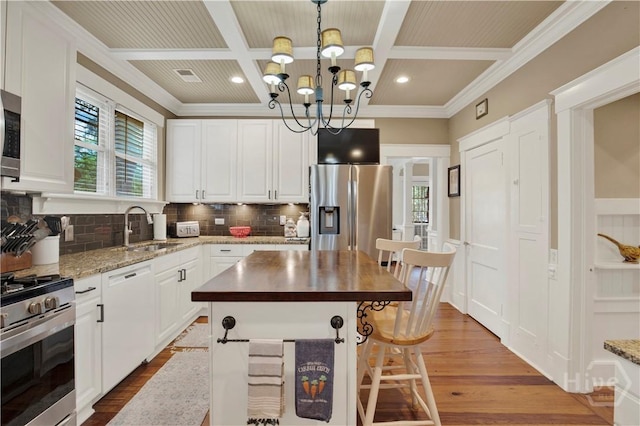 1507 E 49th St, Savannah, GA 31404 - kitchen featuring stainless steel appliances, coffered ceiling, backsplash, wood finished floors, and a chandelier