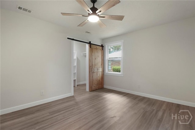 114 Paradise Dr, Savannah, GA 31406 - unfurnished bedroom featuring wood finished floors, a barn door, a spacious closet, and ceiling fan
