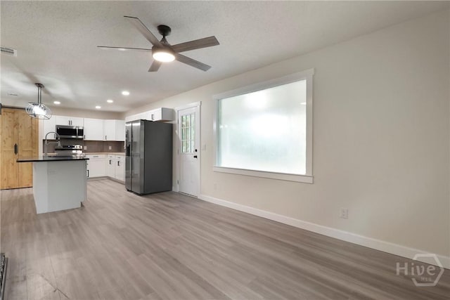 114 Paradise Dr, Savannah, GA 31406 - kitchen with stainless steel appliances, ceiling fan, white cabinets, dark countertops, and light wood-style flooring
