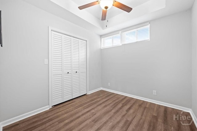 4611 Cumberland Dr, Savannah, GA 31405 - unfurnished bedroom featuring dark wood-style floors, a tray ceiling, a closet, and a ceiling fan