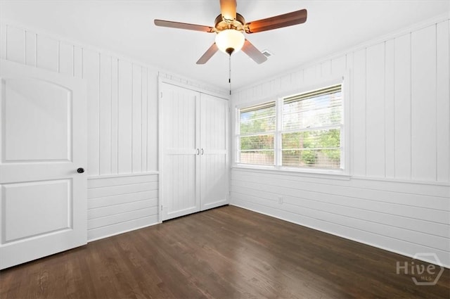 4611 Cumberland Dr, Savannah, GA 31405 - unfurnished bedroom featuring dark wood-style flooring, ceiling fan, a closet, and wooden walls