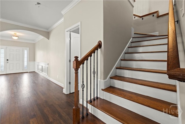219 Byron Dr, Richmond Hill, GA 31324 - foyer featuring arched walkways, crown molding, dark wood finished floors, stairs, and a wainscoted wall