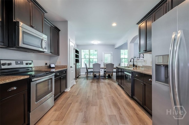 172 Green Paddock Cir, Guyton, GA 31312 - kitchen with stainless steel appliances, light wood-type flooring, dark brown cabinets, light stone counters, and recessed lighting