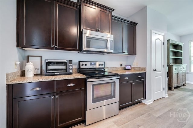 172 Green Paddock Cir, Guyton, GA 31312 - kitchen featuring stainless steel appliances, light wood-type flooring, dark brown cabinetry, and light stone countertops