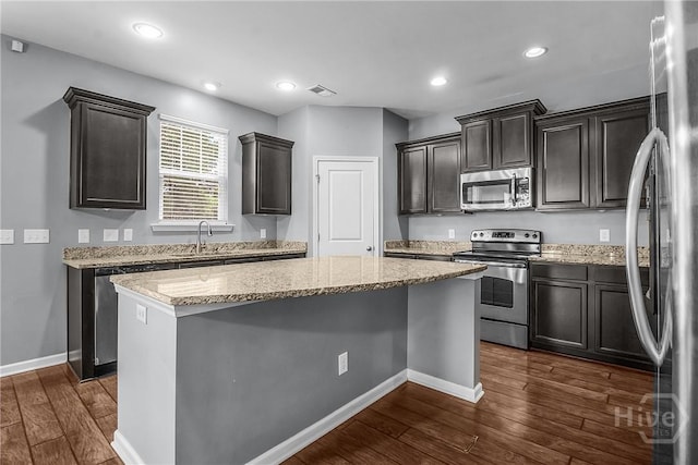 129 Winslow Cir, Savannah, GA 31407 - kitchen featuring appliances with stainless steel finishes, a center island, dark wood-style flooring, light stone countertops, and recessed lighting