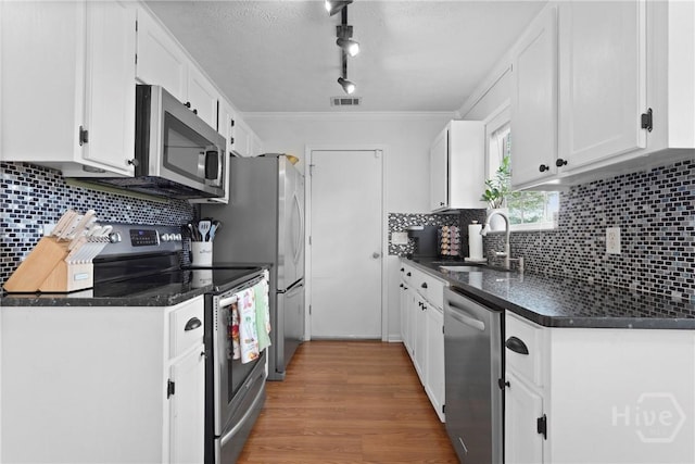 139 Marsh Edge Ln, Savannah, GA 31419 - kitchen with appliances with stainless steel finishes, white cabinetry, backsplash, wood finished floors, and ornamental molding