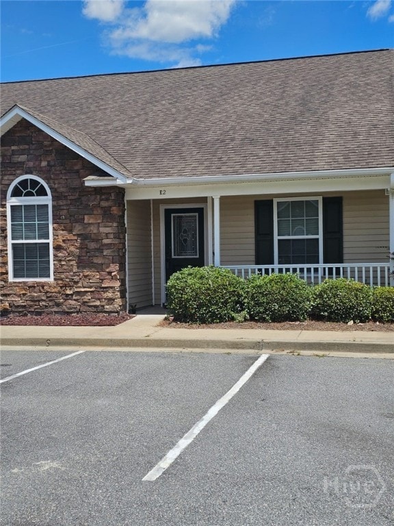 401 Barry Mccaffrey Blvd Unit E2, Hinesville, GA 31313 - view of front of house with stone siding, uncovered parking, a shingled roof, and covered porch