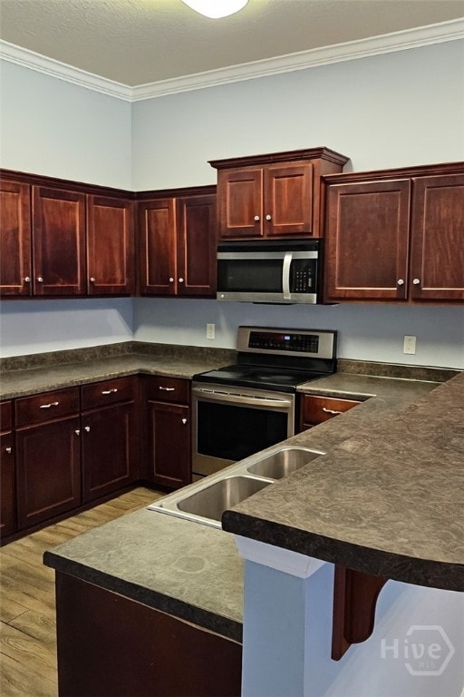 401 Barry Mccaffrey Blvd Unit E2, Hinesville, GA 31313 - kitchen featuring stainless steel appliances, crown molding, dark countertops, light wood-style floors, and a breakfast bar area