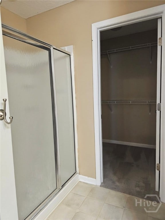 401 Barry Mccaffrey Blvd Unit E2, Hinesville, GA 31313 - full bathroom featuring a stall shower, a walk in closet, and tile patterned flooring