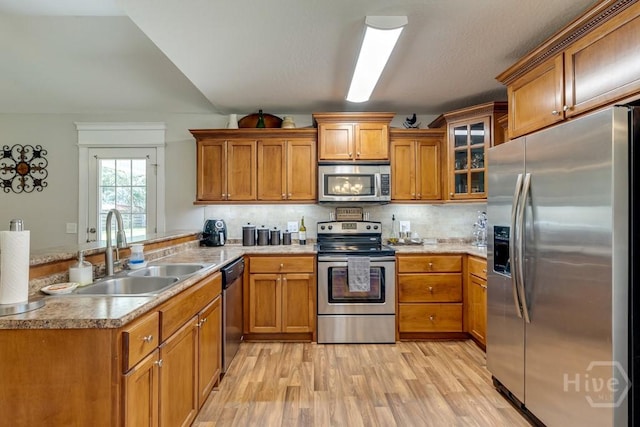 160 Wild Honey Ct, Richmond Hill, GA 31324 - kitchen featuring appliances with stainless steel finishes, a peninsula, brown cabinets, and light wood-style flooring