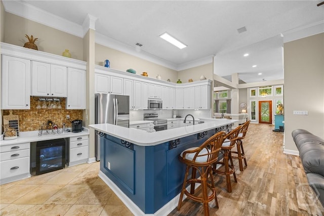 139 Mingarry Dr, Richmond Hill, GA 31324 - kitchen featuring appliances with stainless steel finishes, beverage cooler, white cabinetry, light countertops, and crown molding