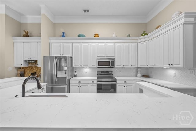 139 Mingarry Dr, Richmond Hill, GA 31324 - kitchen featuring appliances with stainless steel finishes, ornamental molding, white cabinets, light stone countertops, and tasteful backsplash